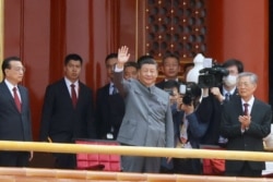 Presiden China Xi Jinping melambaikan tangannya di samping Perdana Menteri Li Keqiang dan mantan presiden Hu Jintao pada akhir acara peringatan 100 tahun berdirinya Partai Komunis China, di Lapangan Tiananmen, Beijing, 1 Juli 2021.