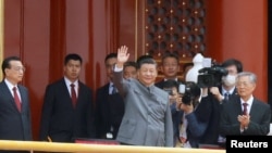 Chinese President Xi Jinping waves next to Premier Li Keqiang and former president Hu Jintao at the end of the event marking the 100th founding anniversary of the Communist Party of China, on Tiananmen Square in Beijing, July 1, 2021. 