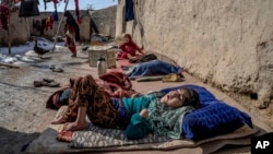 FILE - A sick and disabled girl lies in the open air in a camp for internally displaced families on the outskirts of Kabul, Afghanistan, Feb 6, 2023. The U.N. refugee agency says there are 3.2 million internally displaced people in Afghanistan.