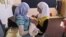 Syrian girls, who fled their home in Anadan with their family hold their relative Mohammed Mustafa who was born five days ago in a school in Kafar Hamra, Syria, August 22, 2012.