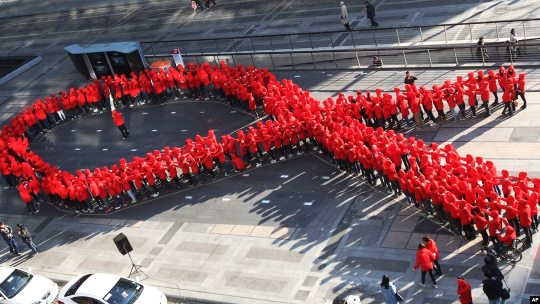 FILE - High school students make a formation in the shape of the red ribbon, the universal symbol of awareness and support for those living with HIV, during a campaign to mark World AIDS Day in Seoul, South Korea, Dec. 1, 2103. 