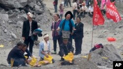 Familiares queman incienso y plegarias en papel para apaciguar la muerte en el sitio de un alud en la población de Xinmo, en la suroriental provincia china de Sichuan, el domingo, 25 de junio de 2017.