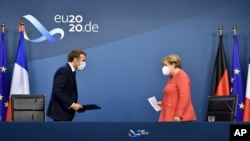 German Chancellor Angela Merkel, right, and French President Emmanuel Macron prepare to address a media conference at the end of an EU summit in Brussels, July 21, 2020. 