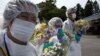 Mourners in protective suits hold flowers at memorial for residents of Okuma, a small town near Fukushima Dai-Ichi nuclear power plant, Japan, July 2011.