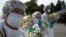 Mourners in protective suits hold flowers at memorial for residents of Okuma, a small town near Fukushima Dai-Ichi nuclear power plant, Japan, July 2011.