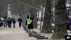 Workers put up fencing in the Mall near Buckingham Palace as preparations begin for the London Marathon, April 18, 2013. 