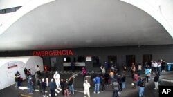 Grupos de personas esperan en el exterior del Hospital Sur de Quito, Ecuador, por noticias de sus familiates ingresados con síntomas de coronavirus el 2 de julio de 2020.