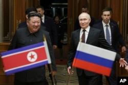 Presiden Rusia Vladimir Putin, kanan, dan pemimpin Korea Utara Kim Jong Un tersenyum selama pertemuan mereka di Bandara Internasional Pyongyang Sunan di luar Pyongyang, Korea Utara, 19 Juni 2024. (Foto: via AP)