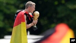 Bastian Schweinsteiger embrasse le trophée de la coupe du monde à l'arrivée de la Mannschaft en Allemagne après le sacre au Brésil, Munich le 15 juillet 2014 (AP Photo/Petr David Josek)