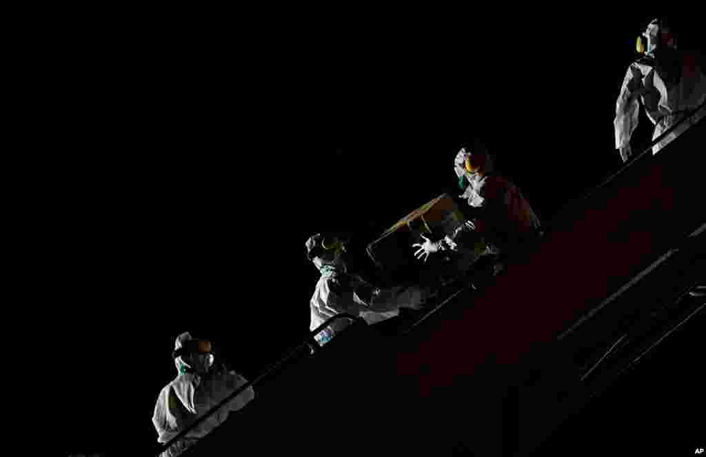 Venezuelan workers wearing protective face masks and suits unload boxes of humanitarian aid as medical supplies and specialists from China arrive to Simon Bolivar International Airport in La Guaira.