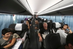 FILE - Migrants sit in a bus that will take them and other migrants to Moneterrey, from an immigration center in Nuevo Laredo, Mexico, July 18, 2019.