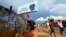 People walk past a campaign poster for incumbent President Ernest Bai Koroma, in Freetown, Sierra Leone, Oct. 19, 2012. 