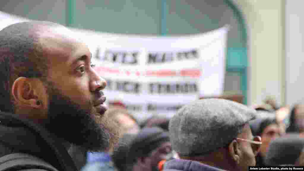 Un manifestant écoutent attentivement les cris du meneur d'un rassemblement réclamant justice sur la mort de Freddie Gray, pendant que la foule bloque l'avenue menant à l'hotel de ville, jeudi 23 avril 2015. (Photo: Victoria Macchi for VOA)