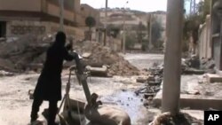 Free Syrian Army fighters drop shell into a firing tube, in Damascus countryside, Syria, Mar 24,2013 (Ugarit News via AP video)