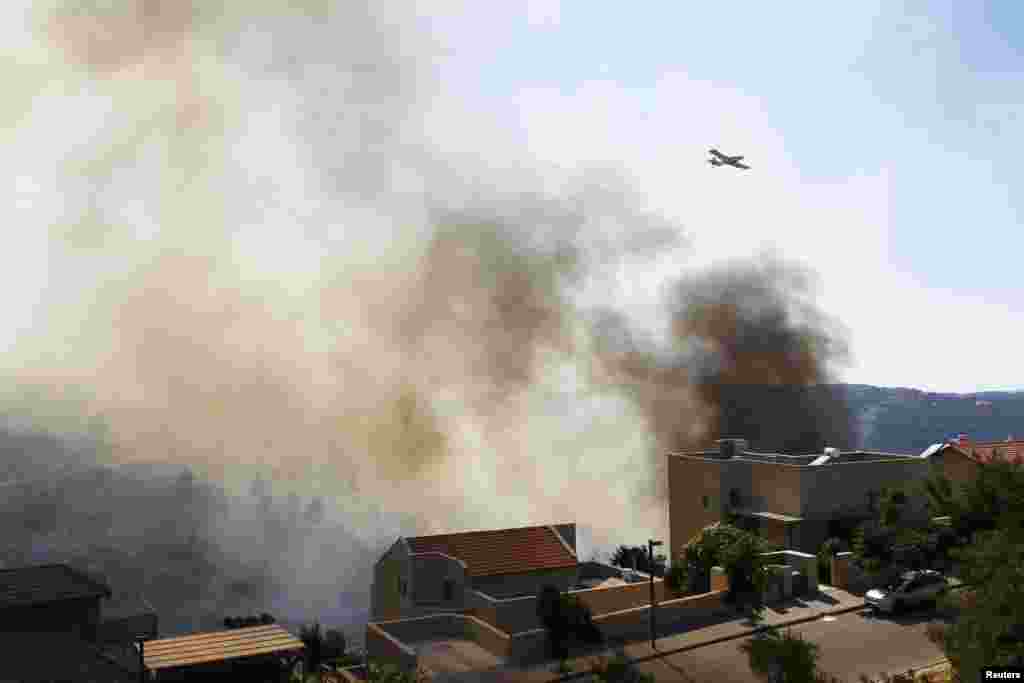 A fire-fighting aircraft works over a forest fire raging near the Israeli village of Aminadav, near Jerusalem, July 2, 2014.