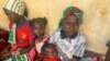 FILE - A woman who fled the violent rebellion in Central African Republic (CAR), sits with her family as they wait for their identification process in the border town of Garoua Boulai, Cameroon, Jan. 7, 2021.