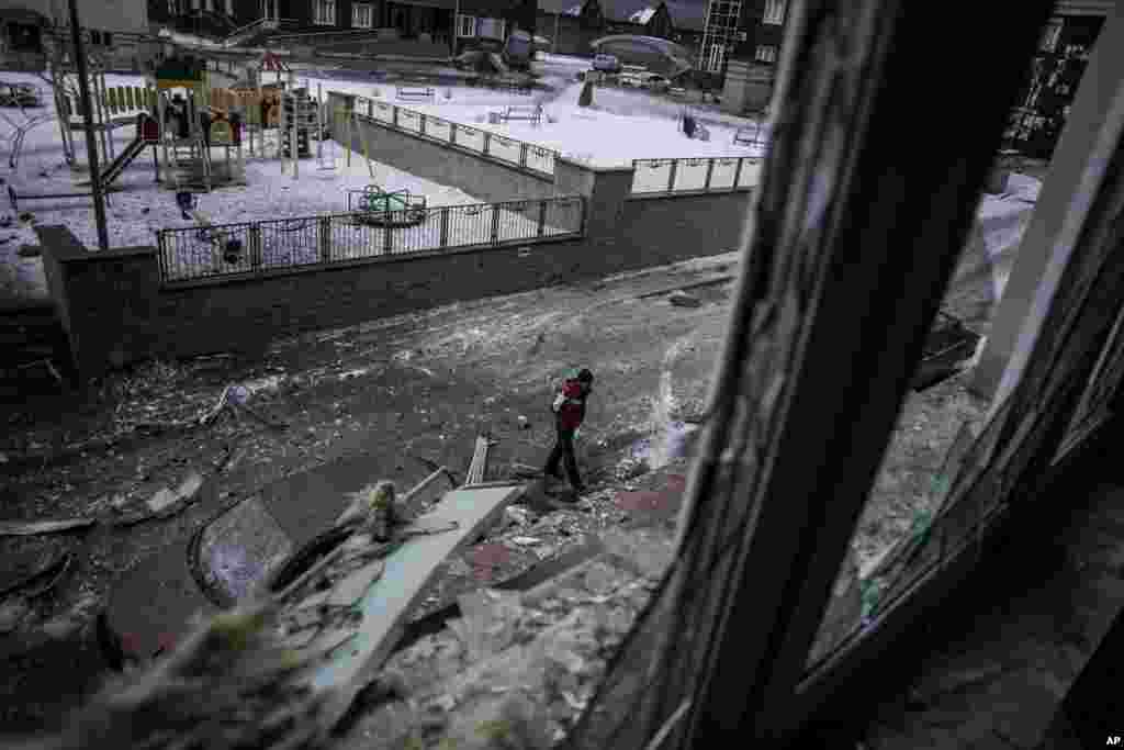 A Ukrainian man walks through the debris after the Ukrainian Army hit a building in the Voroshilovsky area of Donetsk, eastern Ukraine, Jan. 18, 2015.