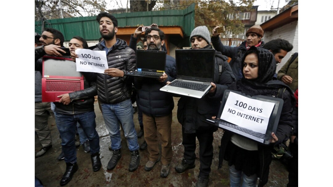FILE - Kashmiri journalists display laptops and placards during a protest demanding restoration of internet service, in Srinagar, November 12, 2019.