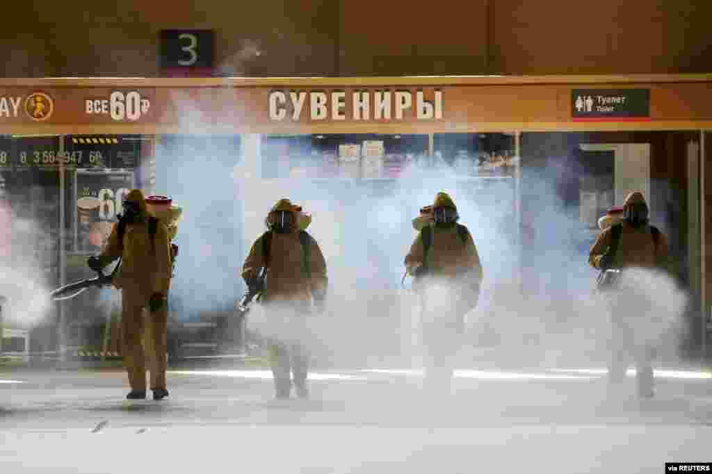 Russia's Emergencies Ministry members wearing personal protective equipment spray disinfectant near a gift kiosk at the Kievsky Railway Station amid the outbreak of the COVID-19 in Moscow. (Credit: Sandurskaya/Moscow News Agency/Handout)