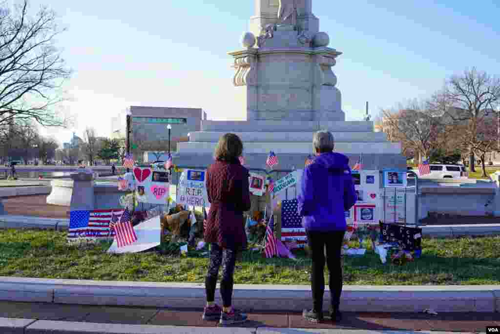 Dos mujeres observan un monumento improvisado en honor a Brian Sicknick, el agente de polic&#237;a del Capitolio que muri&#243; despu&#233;s de ser golpeado por personas que asaltaron el edificio.