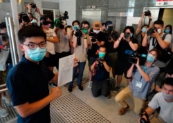 FILE - Hong Kong pro-democracy activist Joshua Wong poses for a picture with nomination papers as he files his candidacy in Legislative Council elections, July 20, 2020.