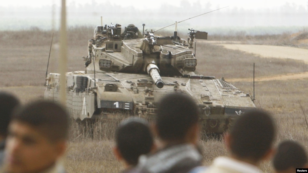 Warga Palestina berdiri di dekat pagar perbatasan Israel-Palestina di Jalur Gaza, memandangi tank Israel yang tengah berjaga di wilayah itu (Foto: dok). Dilaporkan dua orang Palestina terluka terkena tembakan di Gaza tengah (23/12).