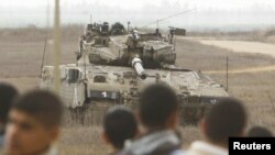 Warga Palestina berdiri di dekat pagar perbatasan Israel-Palestina di Jalur Gaza, memandangi tank Israel yang tengah berjaga di wilayah itu (Foto: dok). Dilaporkan dua orang Palestina terluka terkena tembakan di Gaza tengah (23/12).