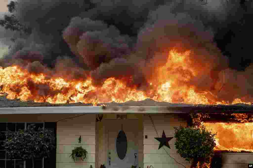 Flames consume a home as the Camp Fire tears through Paradise, California, Nov. 8, 2018.