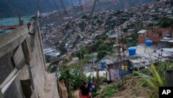 Una mujer con su hijo sube a la colina en el barrio de El Quilombo en Caracas, el 13 de febrero de 2021. [Foto: AP].