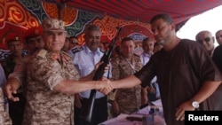 Seorang warga Libya menyerahkan senjatanya ke Kepala Staf Tentara Libya, Yussef al-Mangoush di Martyrs Square, Tripoli (29/9). 