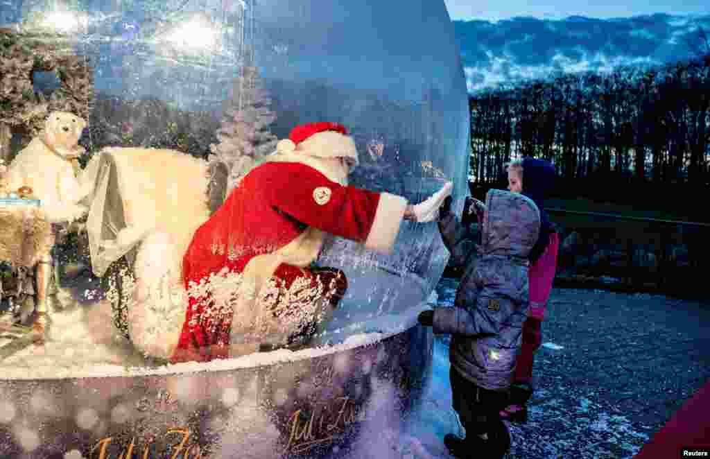 A person dressed as a Santa Claus meets with children while sitting in a &quot;Santa Claus bubble&quot; as he opens Christmas season at Aalborg Zoo, amid the coronavirus outbreak, in Aalborg, Denmark.