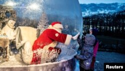 A person dressed as a Santa Claus meets with children while sitting in a "Santa Claus bubble" as he opens Christmas season at Aalborg Zoo, amid the coronavirus outbreak, in Aalborg, Denmark.