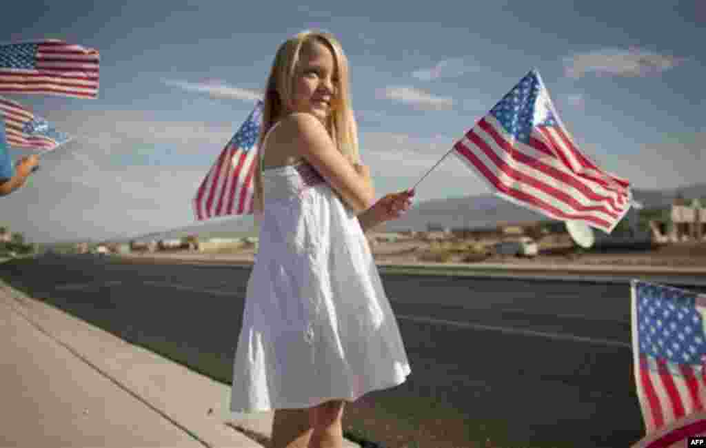 Eight-year-old Madilynn Hallenback waves American flags along state Highway 160 to commemorate the 10th anniversary of the Sept. 11 attacks Sunday, Sept. 11, 2011, in Pahrump, Nev. (AP Photo/Julie Jacobson)