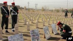 Kurdish soldiers stand in the graveyard for the victims of Halabja massacre, with photos of some of the victims, on its 20th anniversary in Halabja, Iraq, Sunday, March 16, 2008. Some 5,600 people were killed when Saddam Hussein ordered the attack in Ha