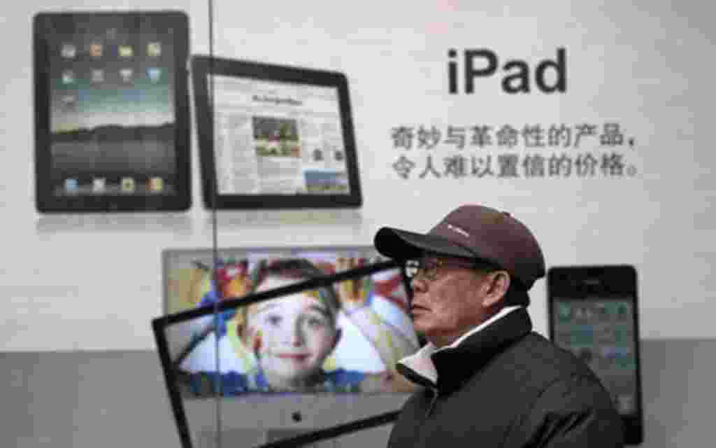 In this photo taken on Jan. 26, 2011 photo, a man stands near Apple's iPad advertisement in Shanghai, China. Apple Inc. said its audits found a doubling in labor, safety and other abuses by its suppliers in 2010, though it praised Taiwanese manufacturer F