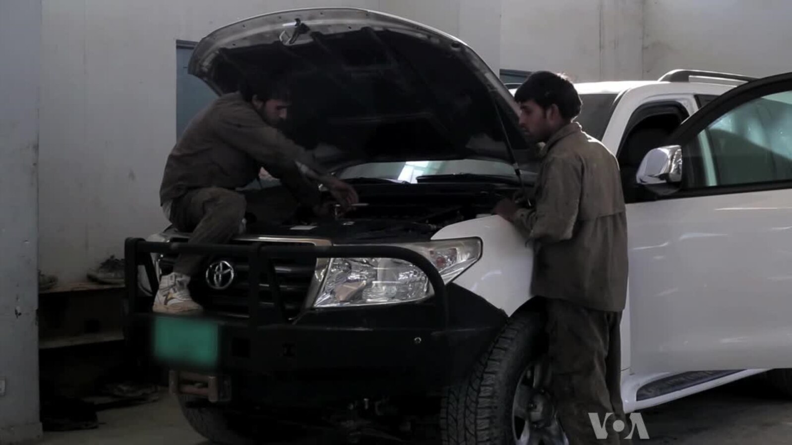 Men work on an armored vehicle at a garage in Afghanistan.