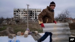 Місцевий житель допомагає сусіду лагодити зруйнований будинок, Архангельське, Херсоншина, 5 грудня 2022. (AP Photo/Evgeniy Maloletka)