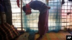 FILE - In this Nov. 27, 2017, photo, a Rohingya man demonstrates what he saw when soldiers bound the hands of dozens of men behind their backs with nylon rope and blindfolded them with scarves taken from women when they massacred his village of Maung Nu in Myanmar's Rakhine state. 