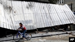 A child rides his cycle as inspects the damaged and burned shops at the main market in Nusseirat refugee camp, central Gaza Strip, March 6, 2020. 