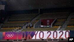 People walk through an empty section of spectator stands during judo competition at the 2020 Summer Olympics, July 24, 2021, in Tokyo, Japan. 