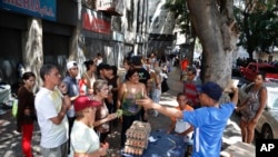 FILE - A food vendor tells shoppers he can't accept their debit cards, the most common form of payment due to inflation, during an electricity blackout in Caracas, Venezuela, March 10, 2019.