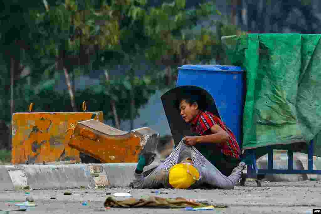 A protester holds onto the shirt of a fallen demonstrator during a crackdown by security forces on anti-coup protests in Hlaing Tharyar township in Yangon, Myanmar, March 14, 2021.