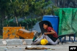 FILE - A protester holds onto the shirt of a fallen demonstrator during a crackdown by security forces on anti-coup protests in Hlaing Tharyar township in Yangon, Myanmar.