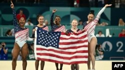 L'Américaine Simone Biles (au centre) et ses coéquipières célèbrent la victoire de l'équipe américaine en finale de gymnastique artistique féminine lors des Jeux Olympiques de Paris 2024 à la Bercy Arena à Paris, le 30 juillet 2024. (Photo de Loic VENANCE / AFP)
