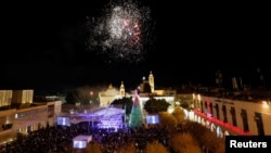 Warga Palestina menyalakan lampu pohon Natal di Lapangan Palungan (Manger Square), di luar Gereja Kelahiran Yesus (Church of the Nativity) di Bethlehem, tepi Barat yang dikuasai Israel, 4 Desember 2021. (REUTERS/Mussa Qawasma)