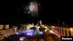 Warga Palestina menyalakan pohon Natal di Manger Square di luar Gereja Kelahiran di Betlehem, di Tepi Barat yang diduduki Israel, 4 Desember 2021. (Foto: REUTERS/Mussa Qawasma)