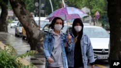 Dua orang warga Ankara, mengenakan masker saat berjalan di sebuah kawasan di ibu kota Turki, 15 Juni 2020.(AP Photo/Burhan Ozbilici)