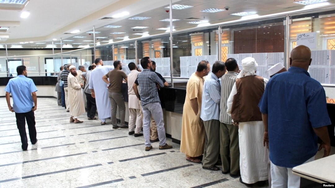 FILE - Libyan people gather in front of a counter in a bank to buy foreign currency in Misrata, Oct. 28, 2018. 