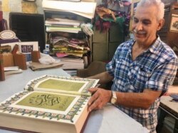 Bookbinder Mohammed Ben Sassi admires an antique quran he is working on. (VOA/Lisa Bryant)