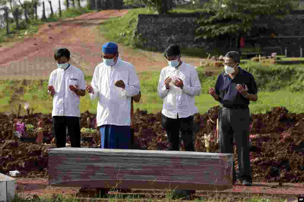 인도네시아 탕게랑 공동묘지의 신종 코로나바이러스 감염 사망자 묘역에서 열린 장례식에서 이슬람 성직자와 친지들이 기도하고 있다.